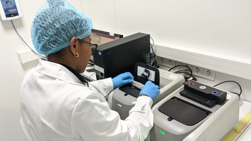 In a laboratory, a laboratory technician with her back turned handles FilmArray.